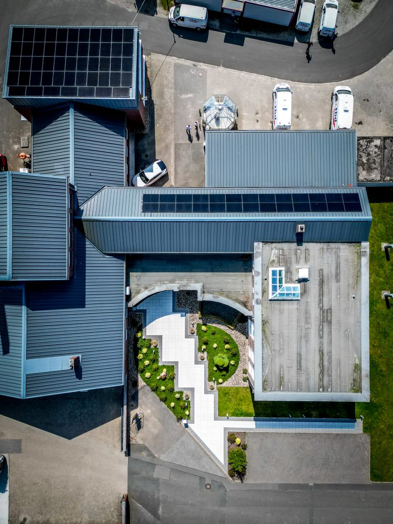 Blick aufs Verwaltungsgebäude mit Eingang und Werkstatt samt der Photovoltaik-Module.