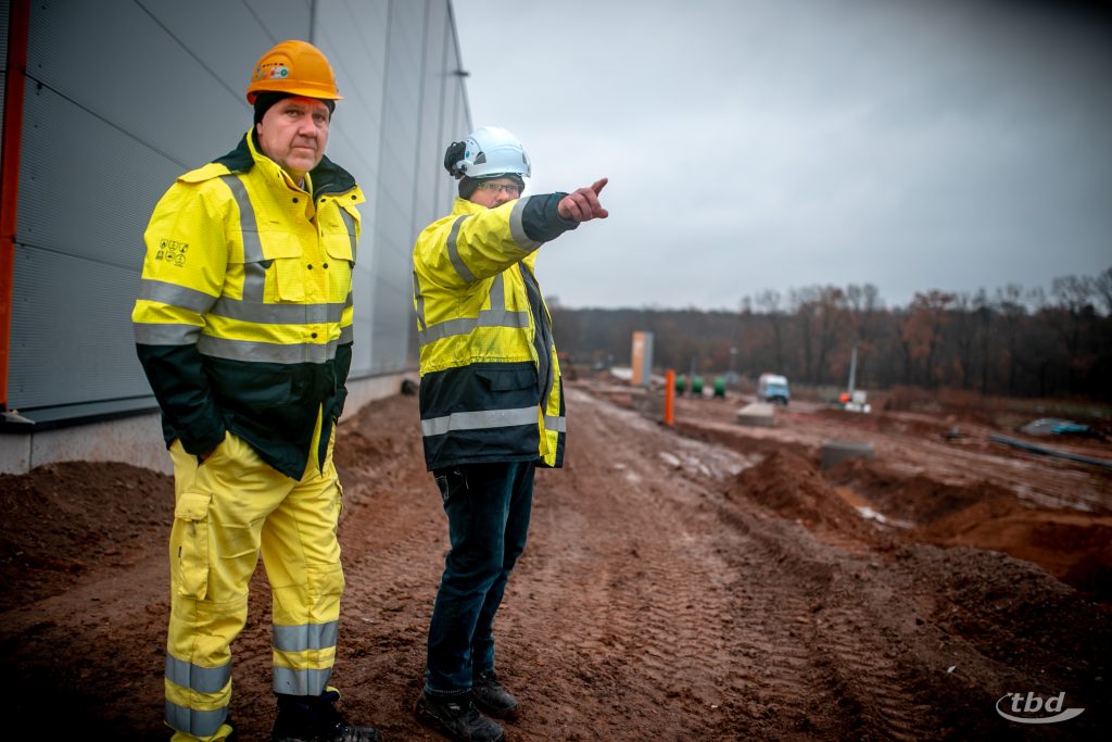 Polier Jan und Projektbüro-Leiter René besprechen auf der Baustelle die nächsten Schritte.