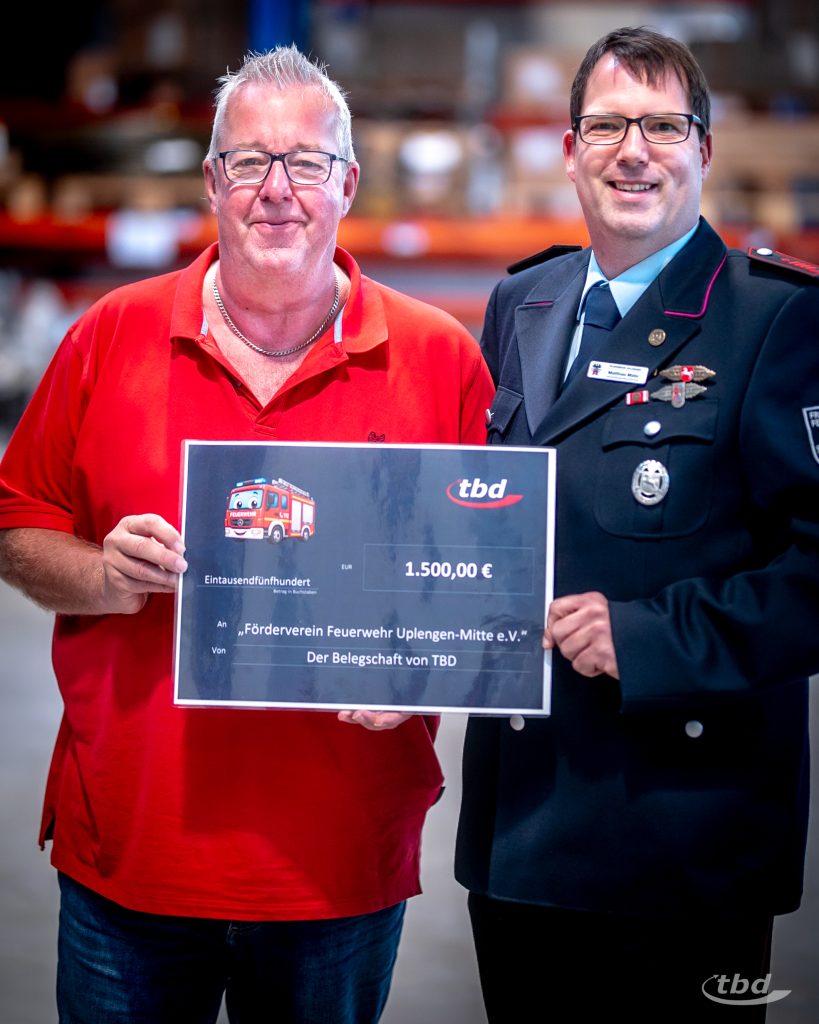 tbd-Betriebsrat Karl Bohlen übergibt den Scheck an seinen Kollegen und Uplengener Jugendfeuerwehrwart, Matthias Matic.